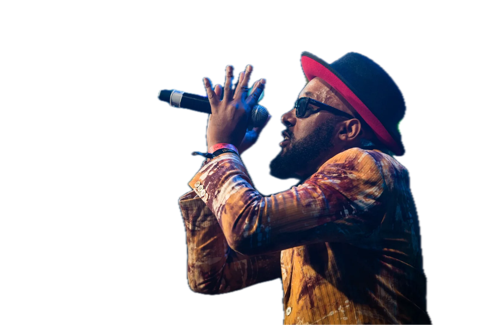 Vox Sambou on stage, singing into a microphone in a red-brimmed hat and a painted jacket
